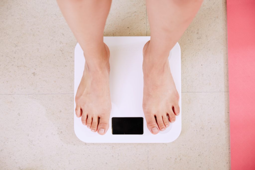A woman measuring weight loss on a scale